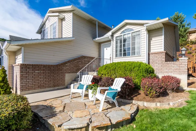 Neutral-sided home with white window trim and chairs on a stone patio